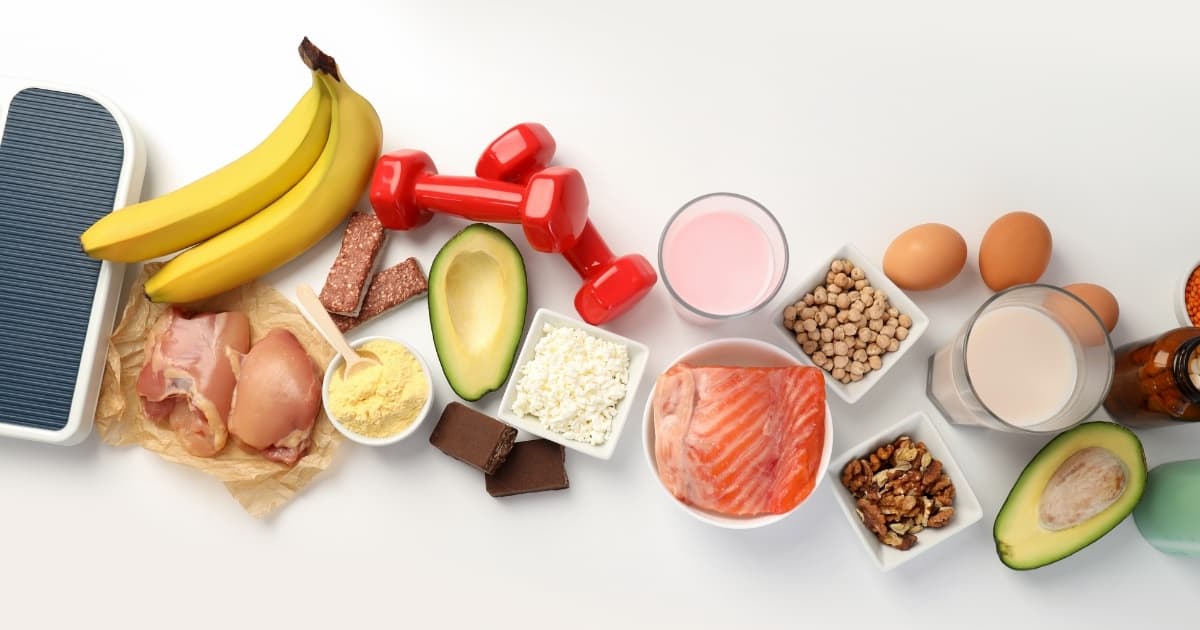 Protein foods, fruit, healthy fats, and light dumbbells arranged for a nutrition plan