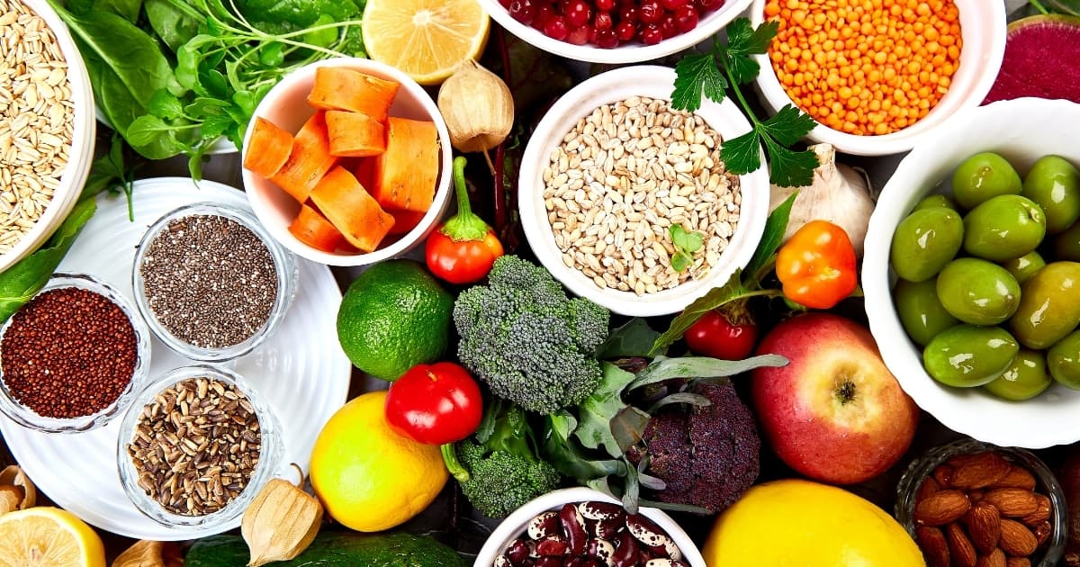 Colorful whole foods including vegetables, grains, fruit, beans, and nuts