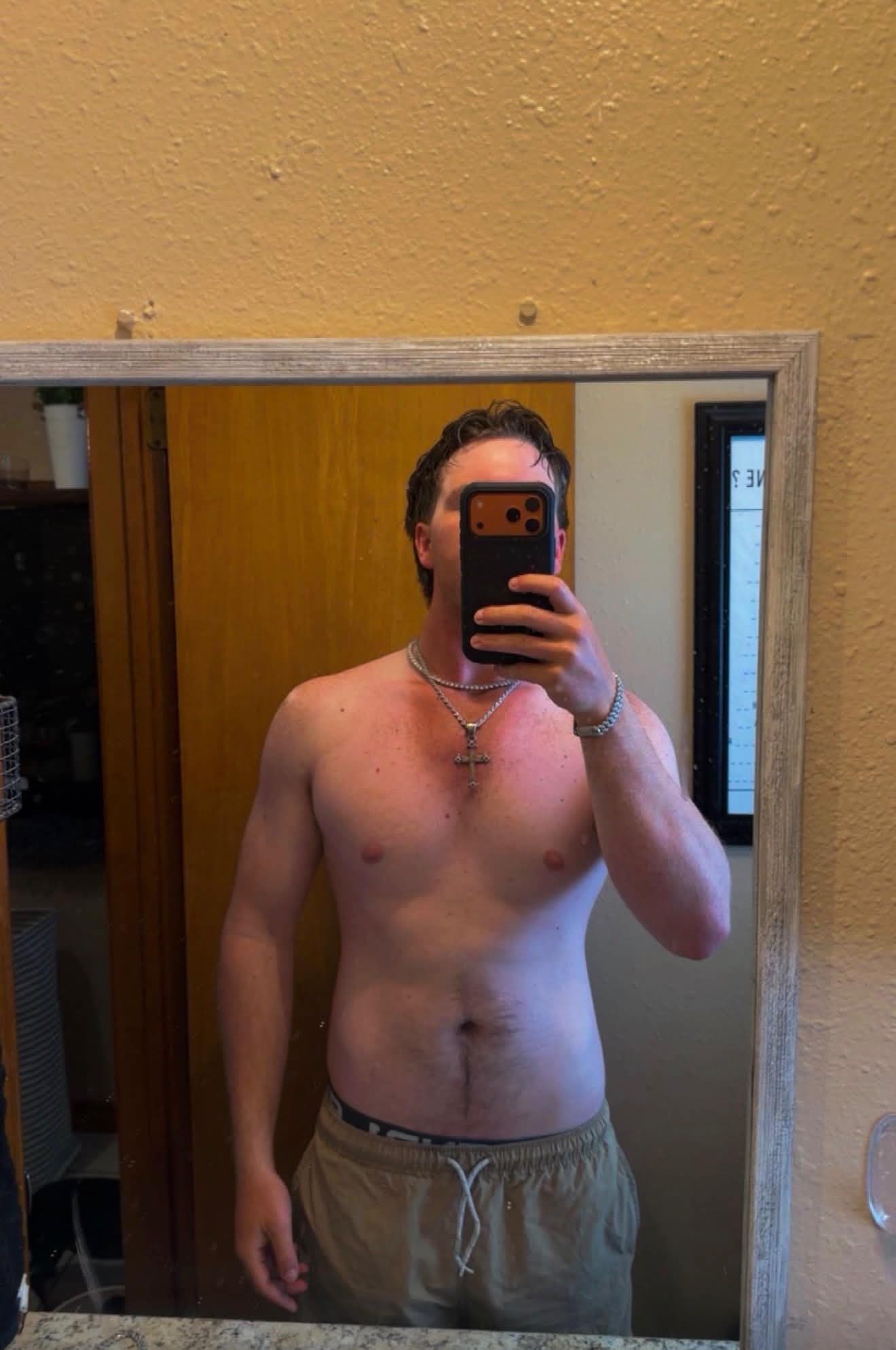 Layne before his physique transformation, taking a mirror progress photo